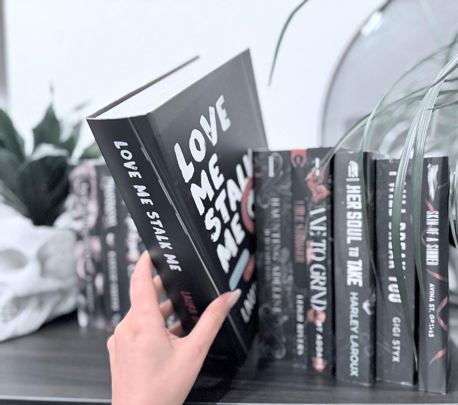 A hand holding the Callahan book styled package for the toy of the dark romance book Love Me Stalk Me by Laura Bishop.