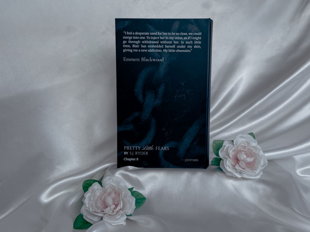 The back cover of the book-like package for Pretty Little Fears by S.J. Ryder next to two white roses.