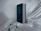 The closed book-like package for Pretty Little Fears by S.J. Ryder next to two white roses.