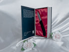 The silicone knife toy inside the opened book-like package for Pretty Little Fears by S.J. Ryder next to two white roses.
