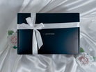 The myplotmate box with a white ribbon and two roses next to it.