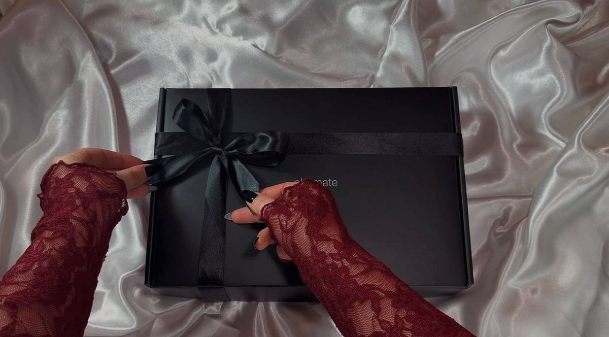 The premium dark romance black mailer box with a black ribbon that contains myplotmate adult toys.