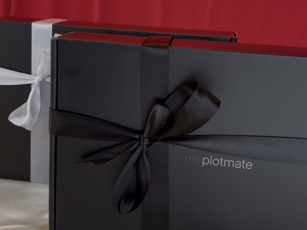 Two myplotmate packages one with a black ribbon and one with a white ribbon.